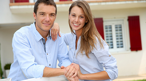 jeune couple devant une maison neuve