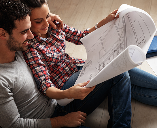 Couple regardant ensemble les plans de leur futur appartement neuf