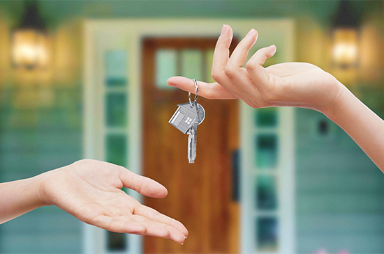 Une personne donnant les clés d'une maison à un acheteur sur le palier d'une maison neuve